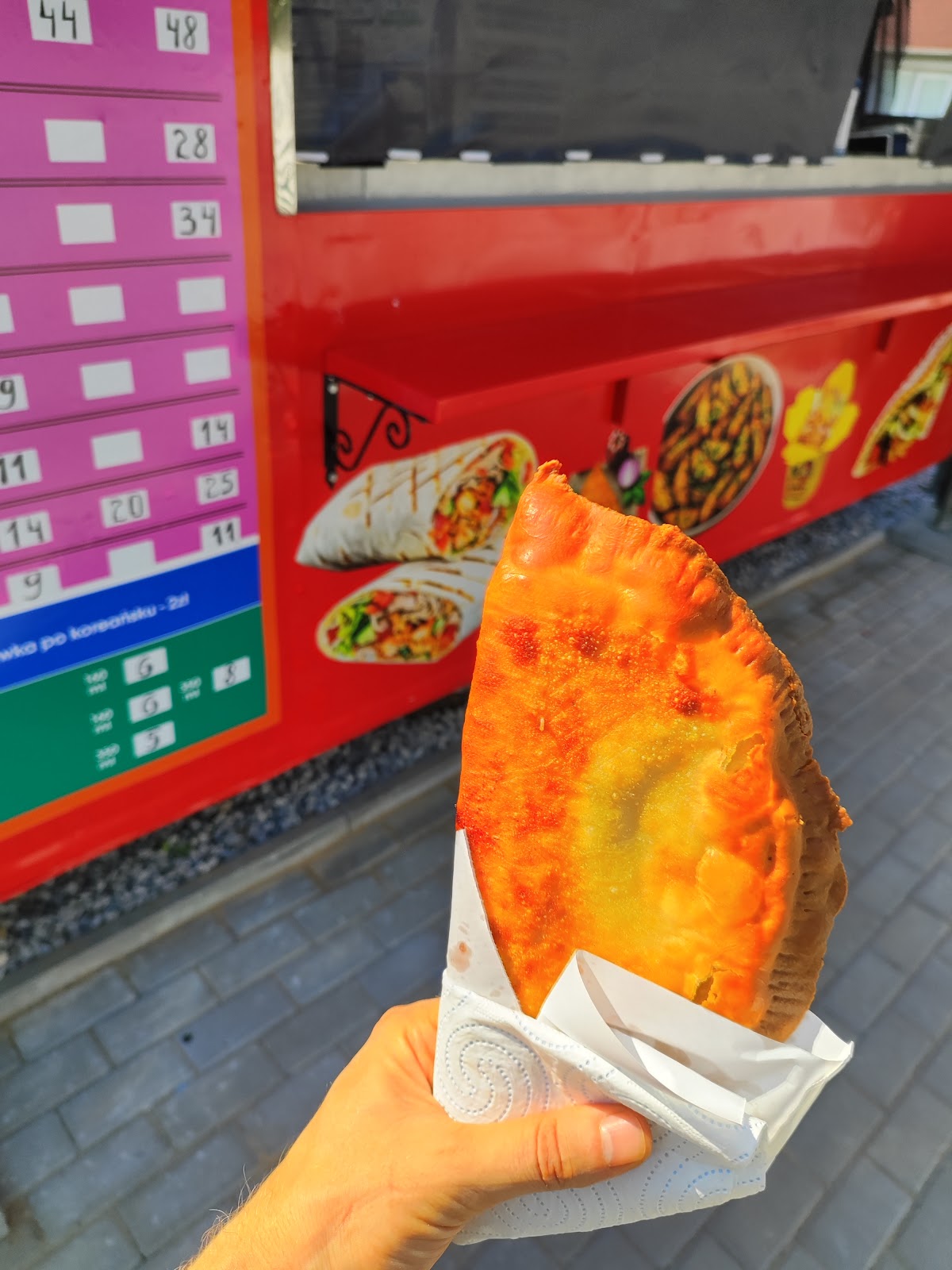 Złocista calzone z chrupiącą skórką, świeżo z pieca, na tle różowego menu VIM Kebab.