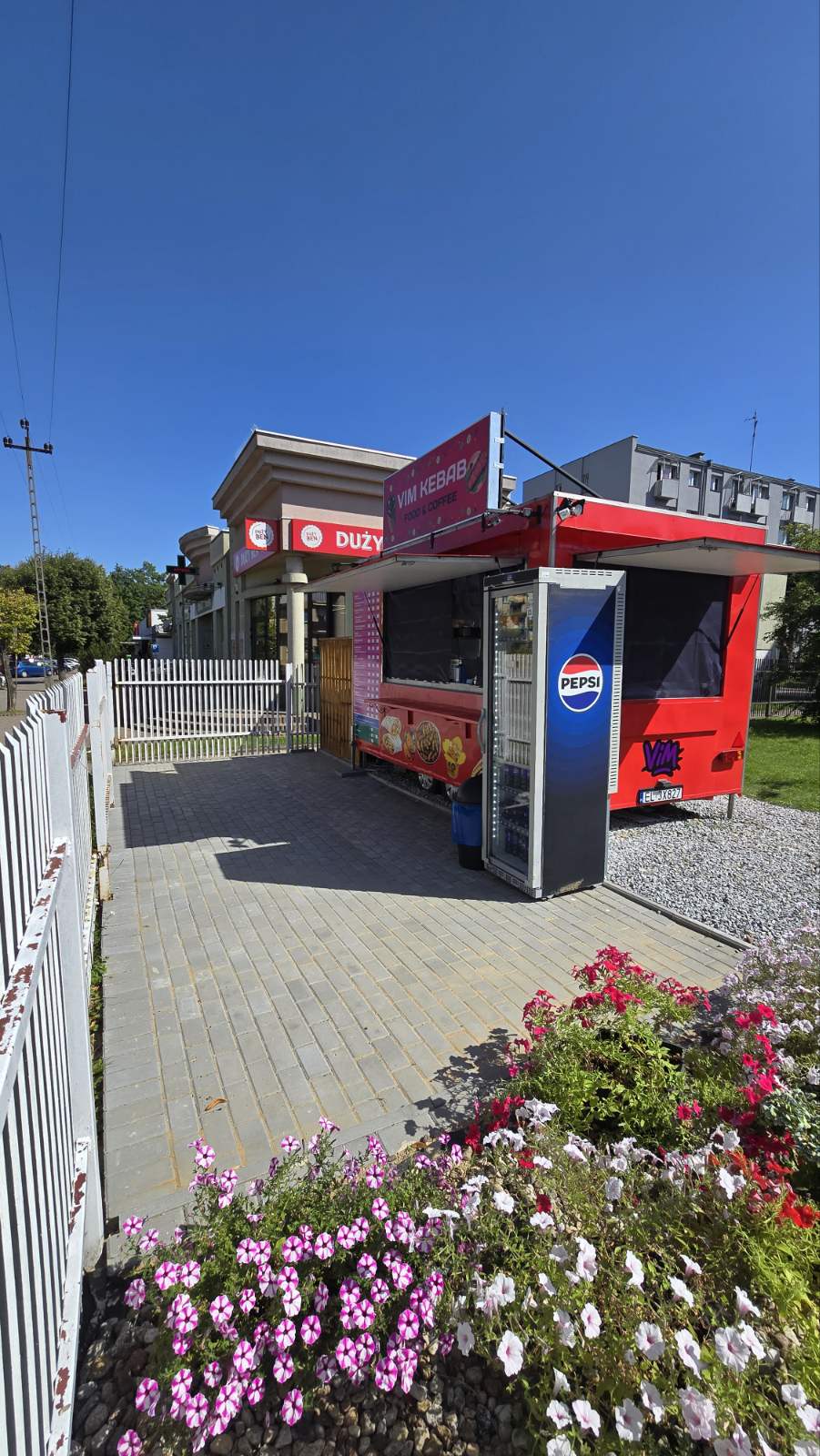 Czerwony food truck VIM Kebab w pełnym słońcu, z otwartym oknem i lodówką Pepsi.