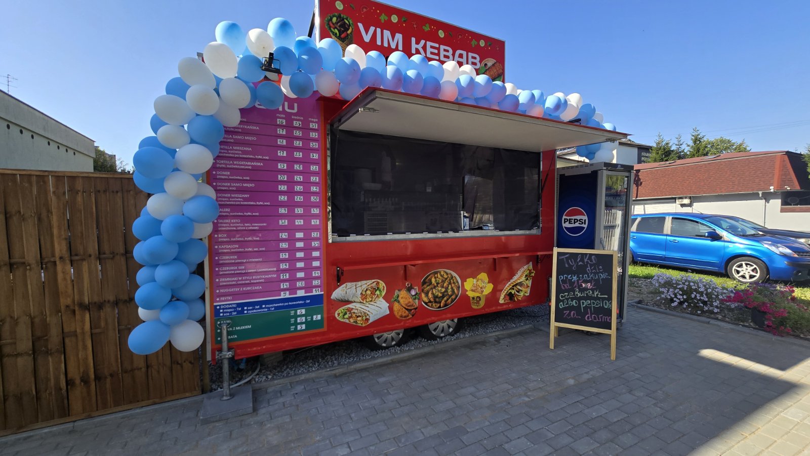 VIM Kebab w dniu otwarcia, ozdobiony niebiesko-białymi balonami i z menu po lewej stronie.