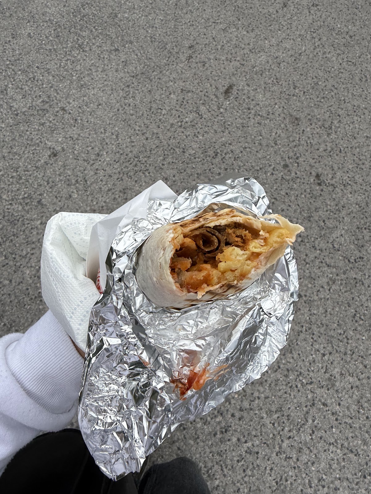 Tortilla z mięsem kebab zawijana w folię aluminiową, gotowa do zabrania w drogę.
